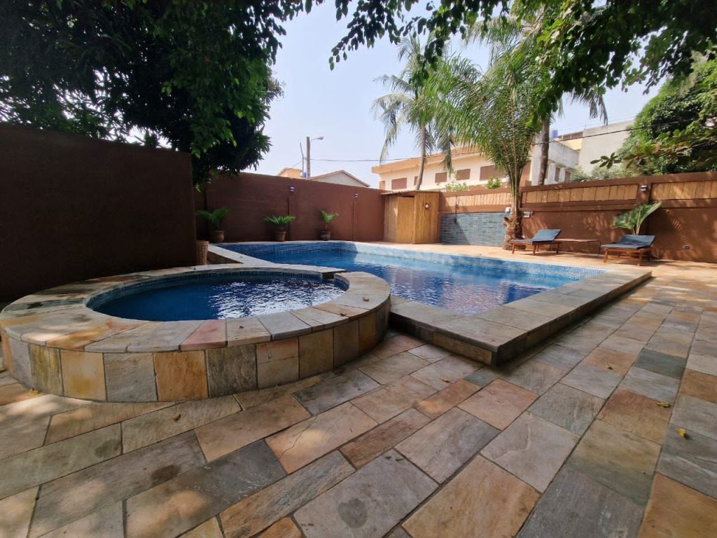 Villa meublée à louer à Fidjrosse, Cotonou : vue extérieure avec un jardin luxuriant et une piscine privée